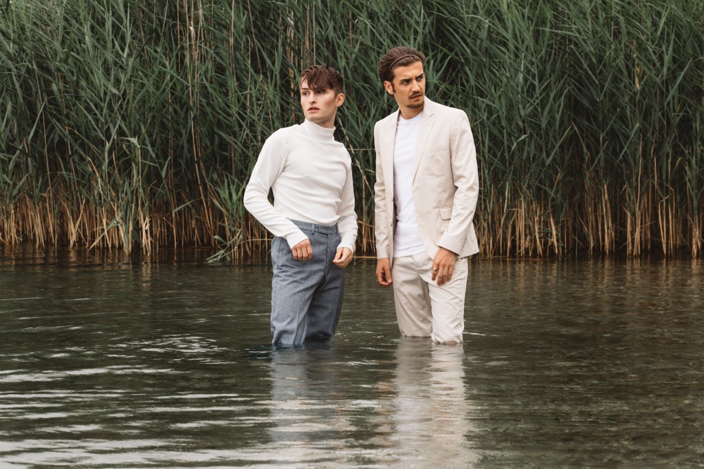 Zwei Männer mit Kleidung im Wasser am See Schilf