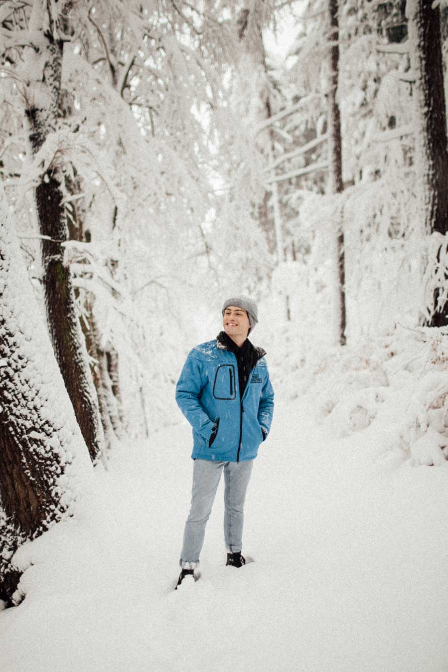 Das sportliche Winter Outfit als blaue Jacke mit Schal in einer Schneelandschaft