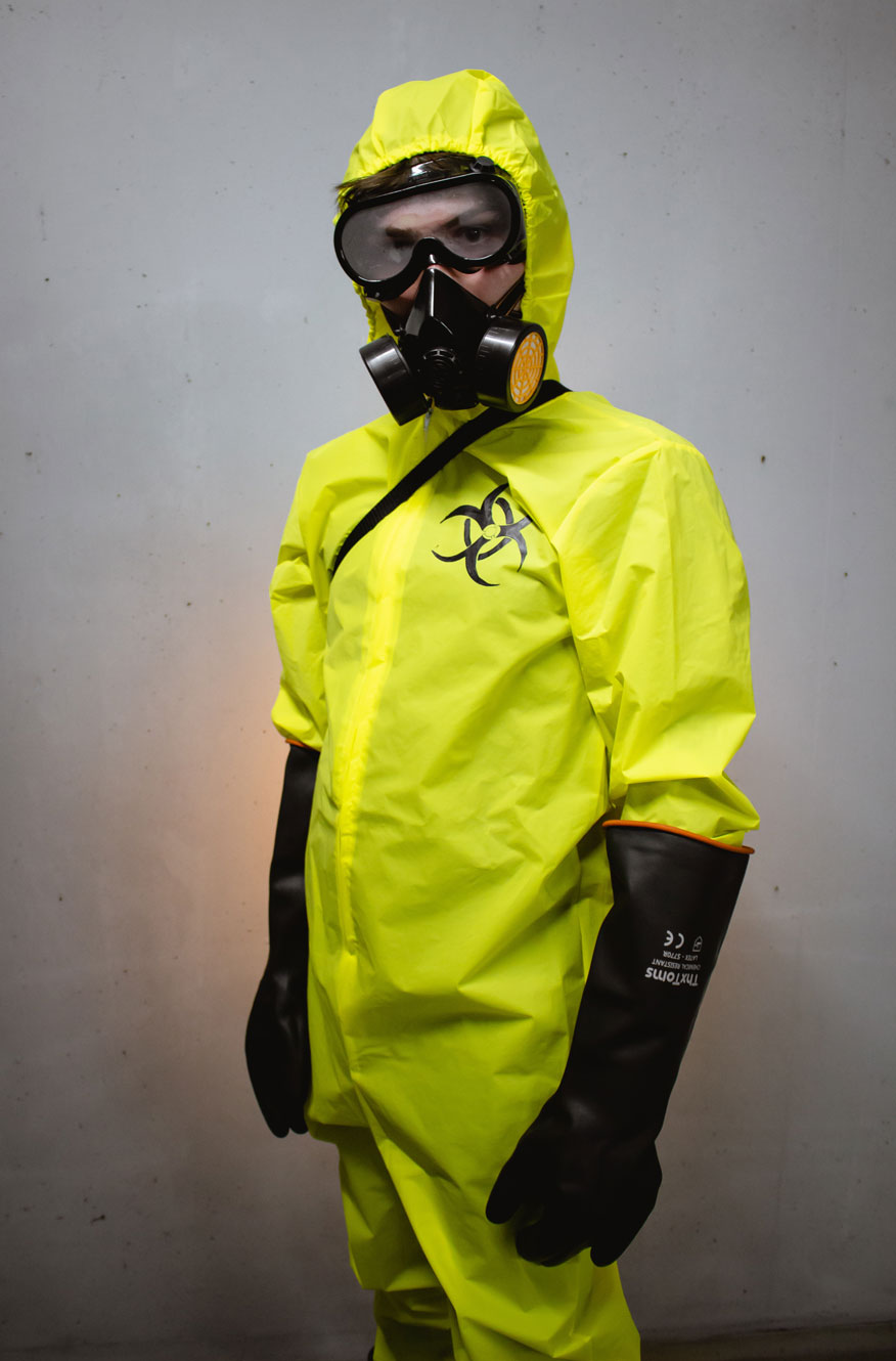 Gasmaske, Gummihandschuhe und PCV Anzug in schwarz und gelb.
